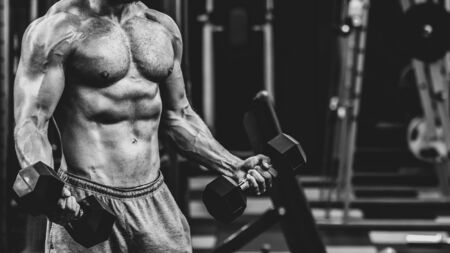 close up of Muscular athletic bodybuilder working hard in gym on dark background, dramatic black and white imageの写真素材