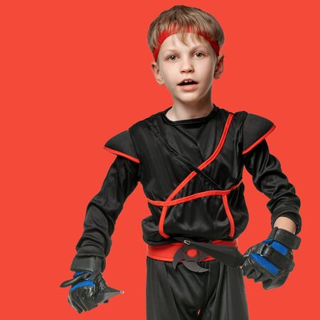 Portrait of healthy active boy exercising with kunai throwing knives on red backgroundの写真素材