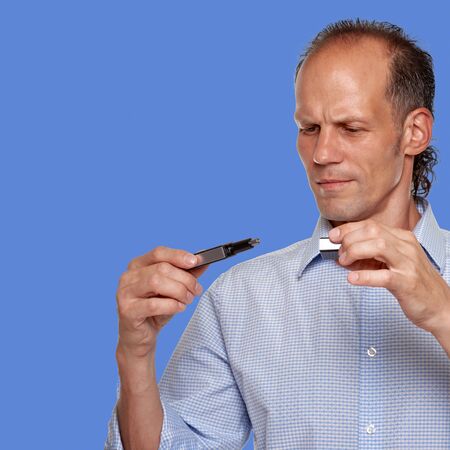 Portrait of handsome man studying work of electric trimmeron blue cornflower color background