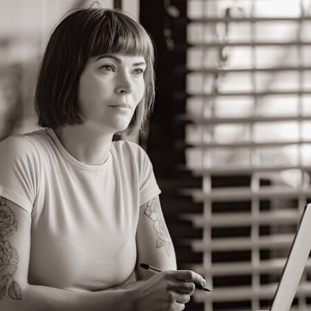Young female copywriter working in modern office with laptop