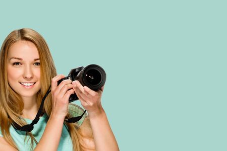 Portrait of young smiling female photographer posing with digital camera