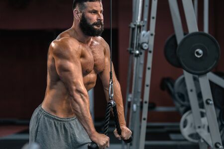 Handsome strong sportsman training in gym and doing pull-ups