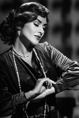 Elegant brunette retro lady posing with wavy hairstyle and jewelryの写真素材