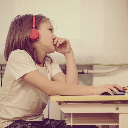 Young schoolboy doing his homework with modern laptop at home