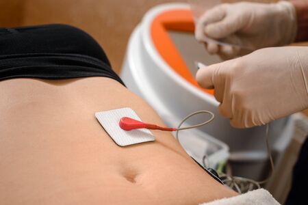 Fat client getting myostimulation procedure for weight loss in beauty salon