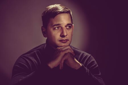 Handsome young man in black sweater posing on vintage backgroundの写真素材