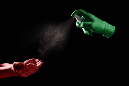 Spraying antibacterial sanitizer on dirty hands with virus isolated on black backgroundの写真素材