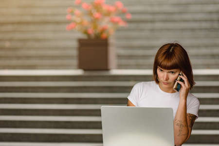 Portrait of young attractive smart woman posing with laptop near gray wall