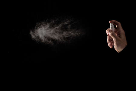 Male hand spraying antiseptic against virus isolated on black background