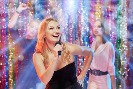 Happy young people dancing and singing karaoke in night club