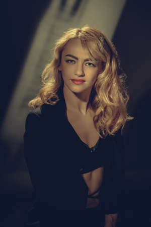 Beautiful fashionable sexy woman with wavy hairstyle posing on vintage backgroundの写真素材