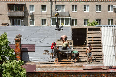 Team of builders installing wooden balks on house roof