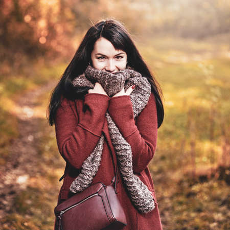 Happy smiling brunette woman enjoying walk in autumn parkの写真素材