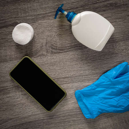 Medical gloves, cotton pads, antibacterial soap and smartphone on wooden tableの写真素材