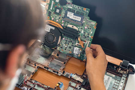 Dnepr, Ukraine- May 04, 2020: Closeup photo of male technician disassembling old laptop for cleaning