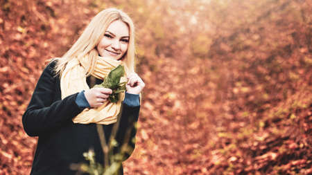 Portrait of beautiful happy young girl wearing warm scarf in autumn forest