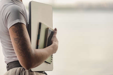 Closeup photo of woman holding laptop, smartphone and notebook outdoor