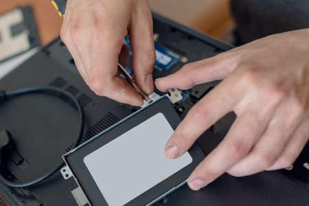 Closeup of male technician replacing ssd disk of laptop