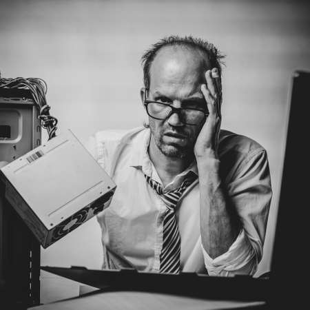 Black and white photo of Portrait of desperate office worker trying to fix broken computer