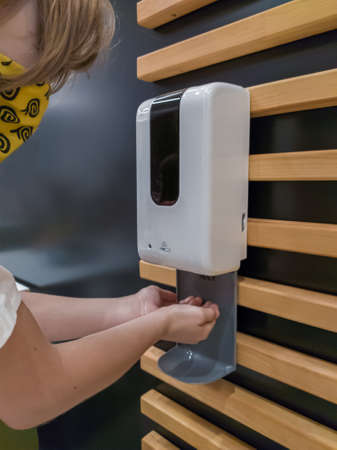 Dnepr, Ukraine - August 08, 2020: Washing hands using automatic sanitizer dispenser in public placeのeditorial素材