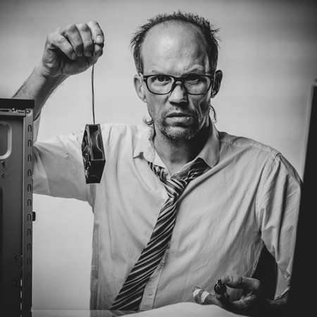 Black and white photo of Unhappy confused man holding computer cooling fan and has no idea what to do with itの写真素材