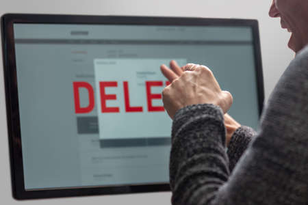 Angry man pointing on computer screen with text Delete. Online banking conceptの写真素材