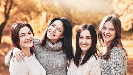 Portrait of four smiling best girlfriends posing in autumn forestの写真素材
