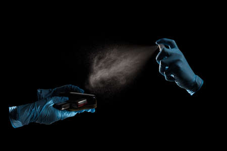 Hand in gloves using antiseptic spray for mobile phones desinfectionの写真素材