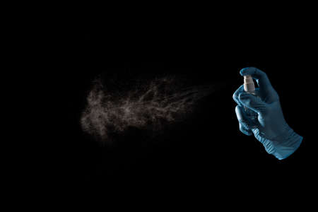 hand in gloves spraying antibacterial disinfectant to avoid virus isolated on black background