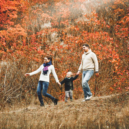 Portrait of beautiful young family on walk in sunny autumn forestの写真素材