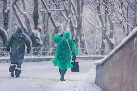Municipal city workers cleaning sidewalk after heavy snowfall
