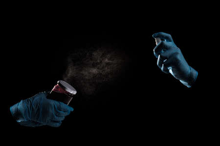 Hands in medical gloves using sanitizer for desinfection jar of jam