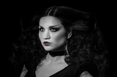 Bright attractive female brunette posing in witch Halloween costume, black and white image with...