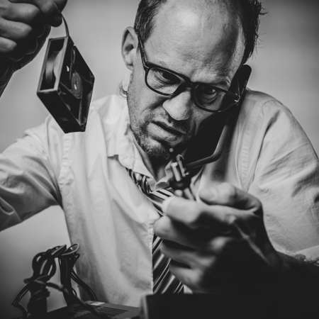 Black and white photo of Confused man holding computer fan and talking with technical supportの写真素材