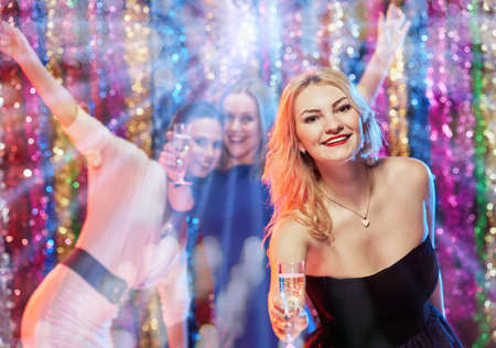 Portrait of cheerful friends celebrating New Year with drinks in handsの写真素材