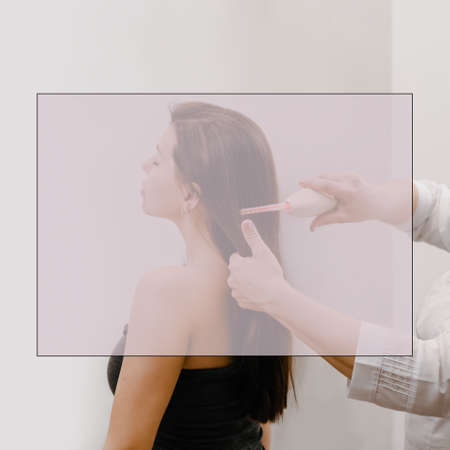 Professional beautician doing darsonval hair treatment procedure for young woman, with field for ad...