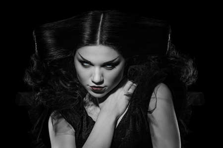 Gothic young woman in witch Halloween costume with bright makeup, black and white image with local color in the iris and lipsの写真素材