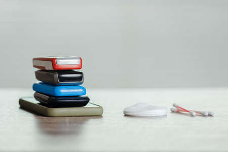Set of mobile phones, cotton pads and buds on wooden table, personal device sanitization reminder