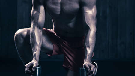 Portrait of strong muscular bodybuilder doing exercises with dumbbells in gymの写真素材