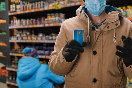 Male customer in medical mask using cards payment method during  pandemicの写真素材
