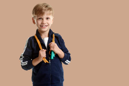 Smiling young sporty boy with skipping rope on salmon shade red backgroundの写真素材