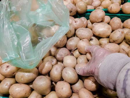 Closeup photo of buyer choosing organic potatoes in grocery store