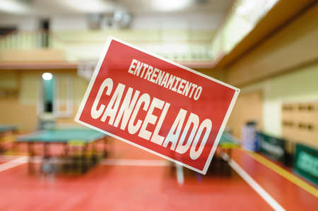 in Spanish inscription sorry workout canceled. gym restrictions during quarantine. Naturally blurred interior of modern gym with tablesの写真素材