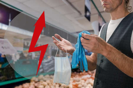 Protective medical mask and gloves are necessary for entering public places. arrow pointer in the form of lightning, the concept of an increase in the cost of products during a crisisの写真素材