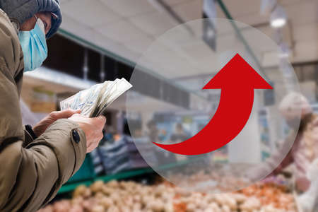 Man in medical mask counting cash money on gray background, elderly people during a pandemic, info arrow showing increaseの写真素材