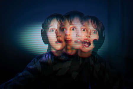 Excited teenager boy playing online computer game at night. home pastime of a teenagerの写真素材