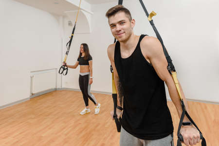 Portrait of handsome young athlete doing suspension training with fitness straps