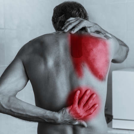 Back view of shirtless man with lower back pain, black and white photo