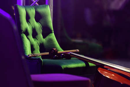 Violin lying on green armchair before symphonic classical concertの写真素材