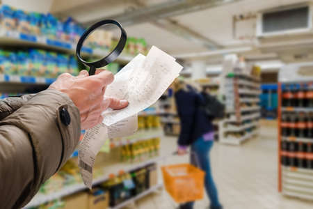Male customer checking grocery bill with magnifying glassの写真素材